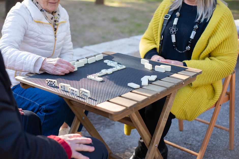 Older adults playing dominoes at an outdoor table