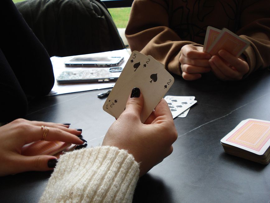 Three people playing a card game at an indoor table